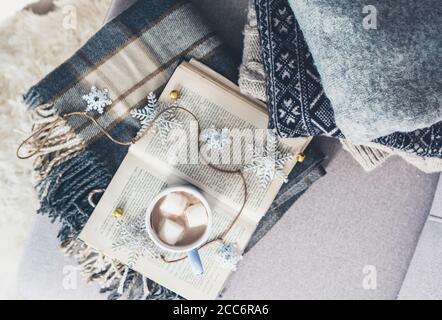 Accoglienti pullover caldi, plaid e tazza di cioccolata calda sono sul divano nel soggiorno Foto Stock