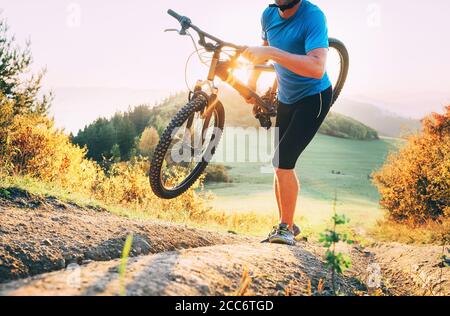 Ciclocross membro della competizione Man mountain biker con la sua moto in su in salita Foto Stock