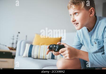 Teenager boy gioca con entusiasmo la console di gioco Foto Stock