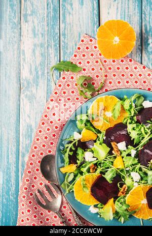 Salsd fresco con barbabietola, arancia e rucola servito su sfondo di legno blu Foto Stock