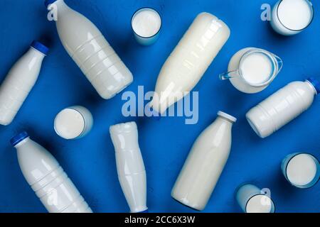 Collezione di bottiglie e bicchieri con latte su sfondo blu, vista dall'alto Foto Stock