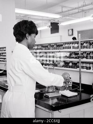 1970 UNA GIOVANE DONNA AFROAMERICANA STUDENTESSA UNIVERSITARIA IN FARMACOLOGIA PREPARAZIONE DELLA MEDICINA IN LABORATORIO - L2526 HAR001 HARS GIOVANE ADULTO INFORMAZIONI DROGHE LIFESTYLE FARMACISTA FEMMINE LAVORI DI LABORATORIO MALATTIA PREPARAZIONE COPIA SPAZIO MEZZA LUNGHEZZA DONNE PERSONE PROFESSIONE FIDUCIA B&W OBIETTIVI DI SUCCESSO SANITARIO ABILITÀ OCCUPAZIONE FELICITÀ ABILITÀ PREVENZIONE AVVENTURA SCOPERTA GUARIGIONE UNIVERSITÀ AFROAMERICANI AFRICAN-AMERICAN DIAGNOSIS CAREERS CHOICE KNOWLEDGE PROGRESS BLACK ETHNICITY DIREZIONE INNOVAZIONE CURA DI SALUTE DI ORGOGLIO NELLE OCCUPAZIONI DI PERDITA DI OPPORTUNITÀ TRATTAMENTO Foto Stock