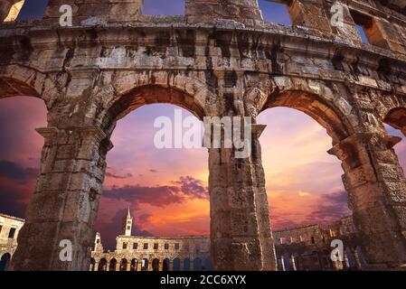 Vista sul campanile della chiesa attraverso gli archi dell'anfiteatro con sfondo viola del cielo dell'alba Foto Stock