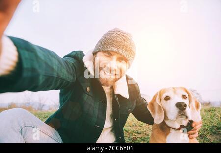 Allegro uomo sorridente scatta foto selfie con il suo migliore amico cane beagle durante la camminata. Immagine concettuale di persone e animali domestici Foto Stock