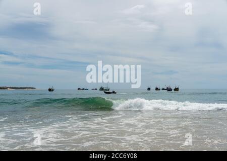 Barche da pesca sul mare, tiro dalla spiaggia, onde in primo piano. Arugam Bay, Sri Lanka Foto Stock