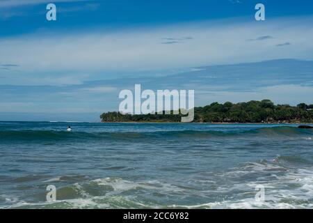 Surfista sul mare, acqua turchese, cielo blu. Arugam Bay, Sri Lanka. Formato verticale Foto Stock