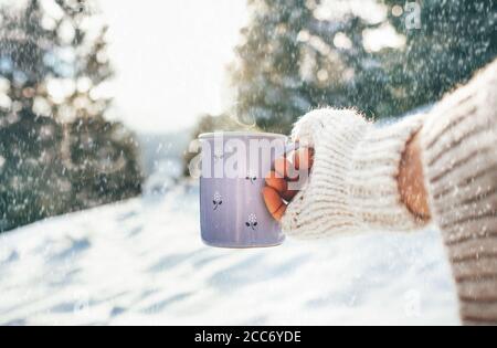 Woman take in hand cup of hot drink. Winter forest glade, bright sunny scene. Point of View POV shot. Foto Stock