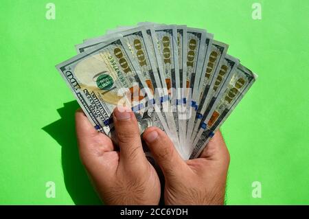 Valuta nazionale degli Stati Uniti. Banconote in dollari USA. Il giovane uomo tiene in mano dollari americani su sfondo verde. USD. Foto Stock