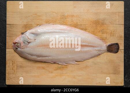 Una suola dover, Solea solea, che è stata skinned prima della cottura. Presentato su un tagliere di legno. Inghilterra GB Foto Stock