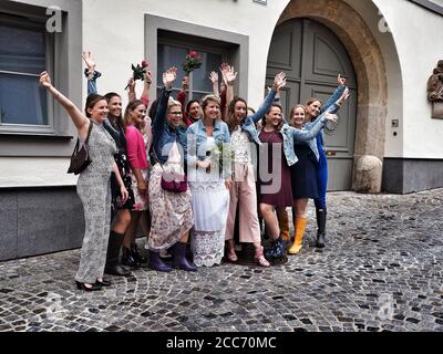 GUMPOLDSKIRCHEN, AUSTRIA - 09/01/2018. Felice sposa caucasica con bridesmaids con le mani in su per la strada. Matrimonio in stivali di gomma in giornata piovosa. Foto Stock