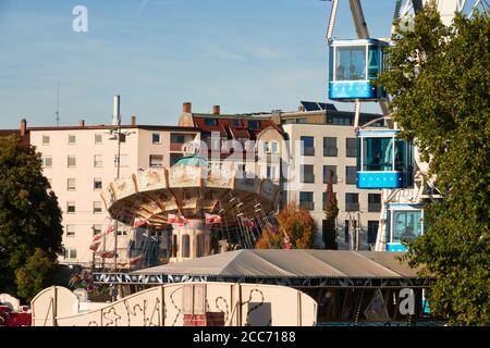 Stuttgart Bad Canstatt, Germania - 11 ottobre 2019: Giostra e catene di gondole in blu al festival folk nell'edificio aziendale di background. Stutt Foto Stock
