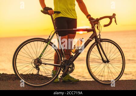 Triatleta professionista allenato con bici da strada al tramonto sull'oceano per la gara di triathlon. Atleta maschile ciclista Foto Stock