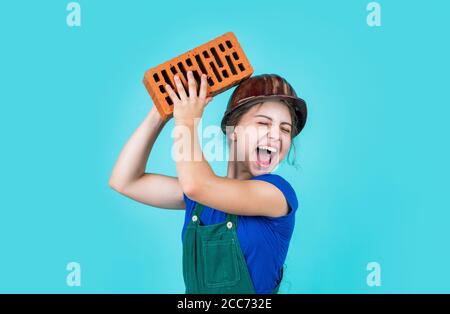 oh no. Piccola ragazza muratore. Imparando come costruire. Piccolo lavoratore nella costruzione del casco da mattone. Architettura costruzione bambino. Bambino in uniforme lavorando intorno muro di mattoni. Concetto di giorno di lavoro. Foto Stock