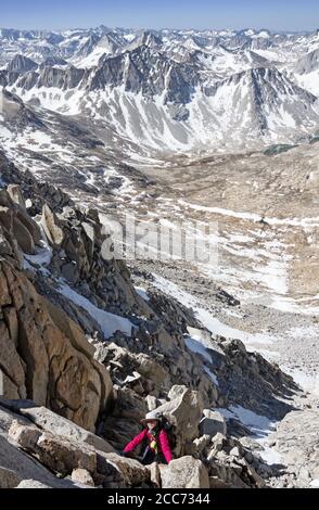 donna che sale sulla ripida terza classe superiore della testata Lo scivolo sud-ovest sul monte Abbot nella Sierra Nevada Montagne con scogliere sotto di lei e. Foto Stock