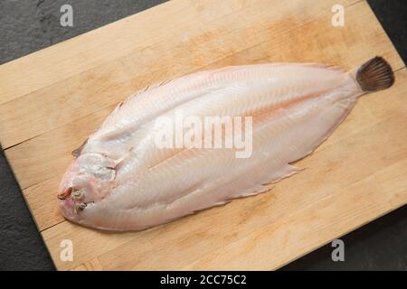 Una suola dover, Solea solea, che è stata skinned prima della cottura. Presentato su un tagliere di legno. Inghilterra GB Foto Stock