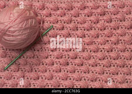 Palla di filo rosa con fondo rosa testurizzato costituito da filo rosa crocheted coperta del bambino nel punto della bobina inoltre conoscere come il punto di ananas Foto Stock