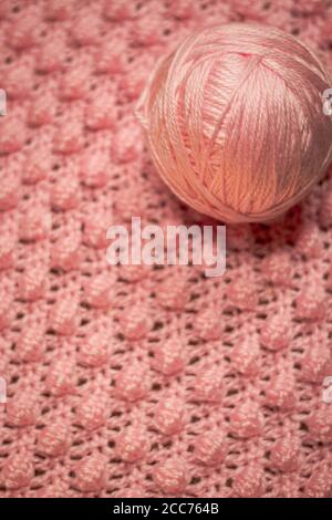 Palla di filo rosa con fondo rosa testurizzato costituito da filo rosa crocheted coperta del bambino nel punto della bobina inoltre conoscere come il punto di ananas Foto Stock