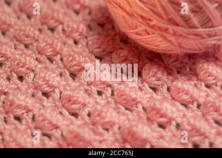 Palla di filo rosa con fondo rosa testurizzato costituito da filo rosa crocheted coperta del bambino nel punto della bobina inoltre conoscere come il punto di ananas Foto Stock