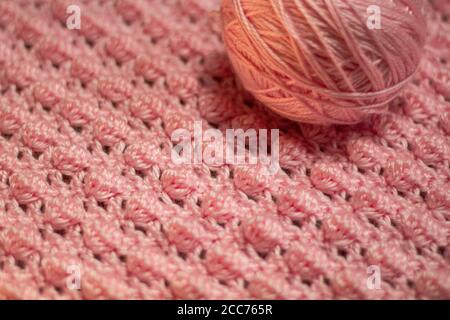 Palla di filo rosa con fondo rosa testurizzato costituito da filo rosa crocheted coperta del bambino nel punto della bobina inoltre conoscere come il punto di ananas Foto Stock