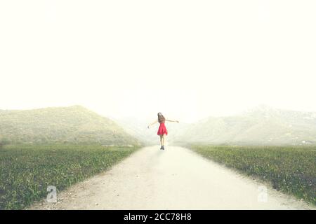 donna con abito rosso cammina felice all'infinito in mezzo della natura Foto Stock