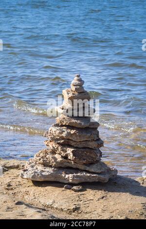 Balanced Rock Stack trovato sulla riva del lago con lappatura ondate dietro Foto Stock