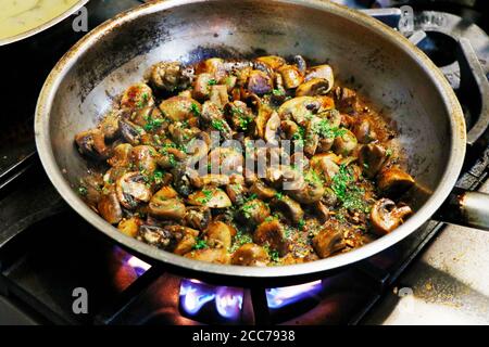 soffriggere i funghi selvatici in una padella sul fuoco in cucina Foto Stock