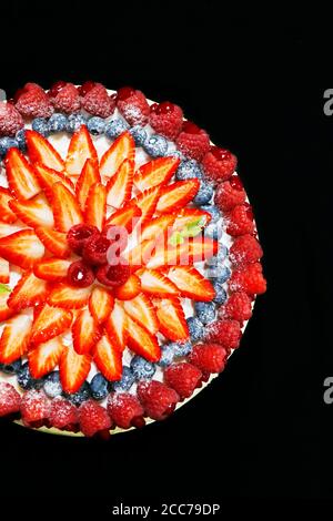 torta di frutta decorata con bacche miste assortite con sfondo nero Foto Stock