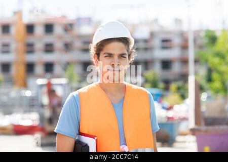 giovane ingegnere edile con casco che lavora all'esterno Foto Stock