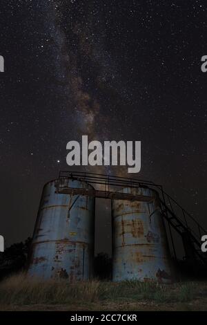 Galactic core Milky Way sorge dietro due serbatoi di stoccaggio di acqua inutilizzati in aride pianure del texas centrale occidentale. Composte in primo piano con stellare. Foto Stock