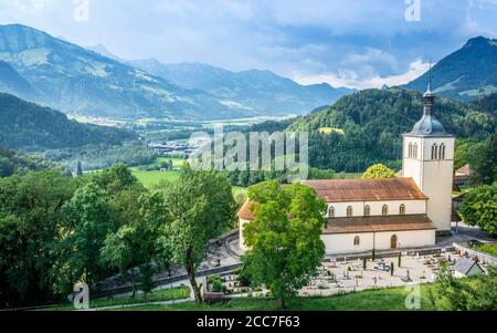 Panorama della città di Gruyeres con la chiesa di San Teodulo e cimitero Vista e montagne sullo sfondo a la Gruyere Friburgo Svizzera Foto Stock