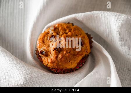 Muffin fatti in casa con uvetta su sfondo di legno. Cupcake in una muffa di carta su un tovagliolo bianco. Foto Stock