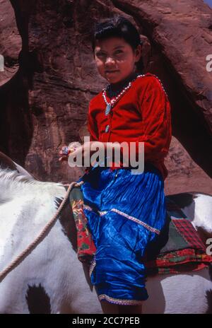 Giovane ragazza indiana Navaho sul suo cavallo, in abbigliamento tradizionale. Monument Valley, Arizona, Stati Uniti. Fotografato agosto 1963. Foto Stock