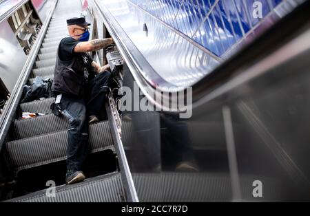 Monaco, Germania. 17 agosto 2020. Emilijan Stamfar, un dipendente di Stadtwerke München, installa lampade UV su una scala mobile a Marienplatz S-Bahn e U-Bahn. Stadtwerke München (SWM) e Münchner Verkehrsgesellschaft (MVG) stanno conducendo un test a lungo termine per esaminare la disinfezione dei corrimano sulle scale mobili con luce UV. Credit: Sven Hoppe/dpa/Alamy Live News Foto Stock