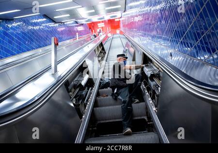 Monaco, Germania. 17 agosto 2020. Emilijan Stamfar, un dipendente di Stadtwerke München, installa lampade UV su una scala mobile a Marienplatz S-Bahn e U-Bahn. Stadtwerke München (SWM) e Münchner Verkehrsgesellschaft (MVG) stanno conducendo un test a lungo termine per esaminare la disinfezione dei corrimano sulle scale mobili con luce UV. Credit: Sven Hoppe/dpa/Alamy Live News Foto Stock