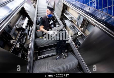 Monaco, Germania. 17 agosto 2020. Emilijan Stamfar, un dipendente di Stadtwerke München, installa lampade UV su una scala mobile a Marienplatz S-Bahn e U-Bahn. Stadtwerke München (SWM) e Münchner Verkehrsgesellschaft (MVG) stanno conducendo un test a lungo termine per esaminare la disinfezione dei corrimano sulle scale mobili con luce UV. Credit: Sven Hoppe/dpa/Alamy Live News Foto Stock