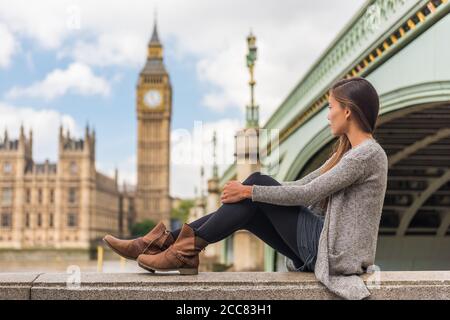 La giovane donna londinese rilassa il pensiero pensivo da sola alla torre Big ben nella città urbana d'Europa. Ragazza asiatica solo triste o depresso seduta all'aperto nel Foto Stock