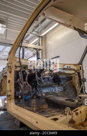 in un negozio di riparazione auto c'è un'auto spogliata senza volante Foto Stock