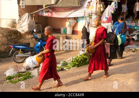 Thailandia: Monaci buddisti al mattino presto attraverso il mercato di Doi Mae Salong (Santikhiri), provincia di Chiang Rai. Doi Mae Salong era un tempo un impoverito, pesantemente armato Kuomintang (KMT) avamposto, è oggi una tranquilla oasi di giardini del tè, frutteti e case in stile Yunnanese. Foto Stock