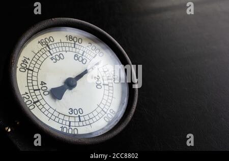 Primo piano del quadrante grande del contagiri. Vecchio strumento di misurazione meccanico su sfondo nero. Spazio di copia. Messa a fuoco selettiva. Foto Stock