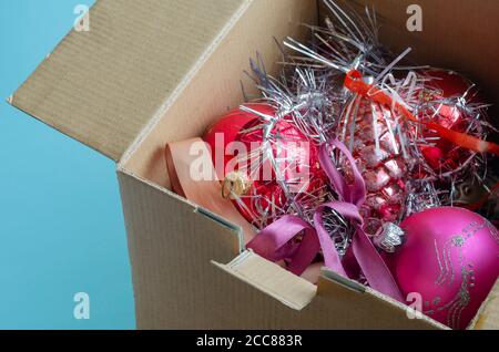 Scatola di cartone piena di decorazioni dell'albero di Natale. Decorazioni e tindel di albero di Natale in vetro casuale. Festeggiamo Natale e Capodanno. Vista dall'alto su Foto Stock