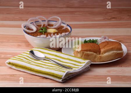 PAV Bhaji è un piatto fast food indiano, curry vegetale denso e piccante, fritto e servito con un rotolo di pane morbido/panino paav e burro. Foto Stock