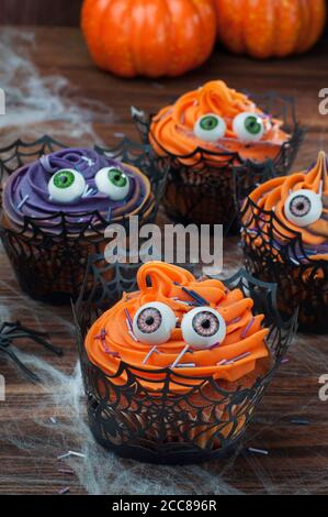 I cupcake di Halloween decorati con gli occhi con panna montata e spruzzano Foto Stock