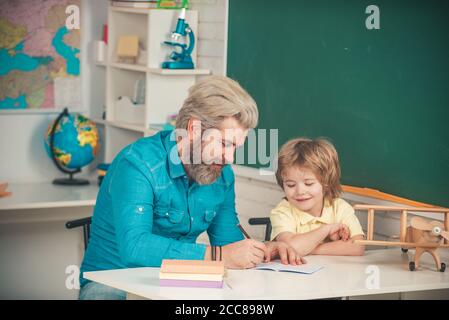 Insegnante e allievo in classe. Studio della casa del bambino e formazione domestica. Istruzione degli allievi. Tutoraggio post-scuola. Allievo carino e la scuola del suo padre Foto Stock