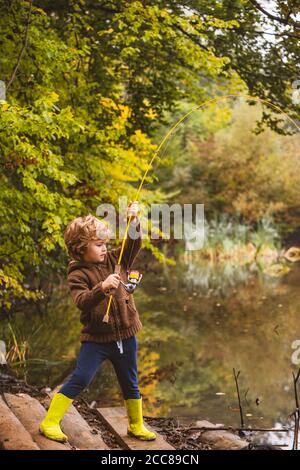 Foto di capretto che tira l'asta mentre pesca il fine settimana. Foto Stock