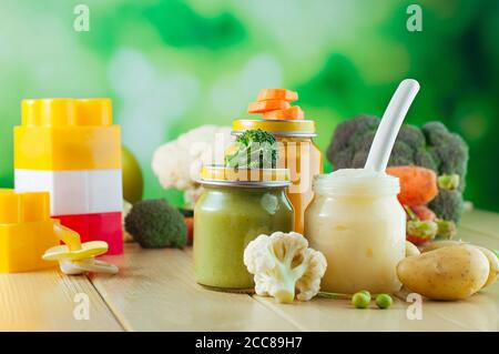Vasetti con purè con cucchiaio vicino a frutta e verdura fresca Foto Stock