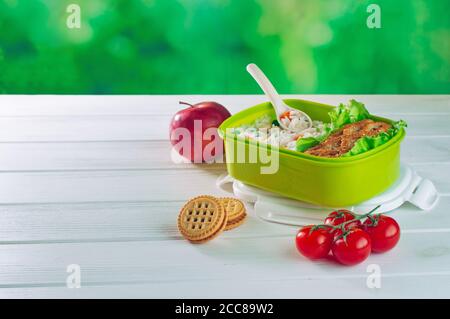 Pranzo al sacco riempito di riso e sandwich vicino a mela, pomodori e biscotti Foto Stock