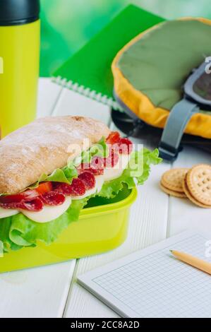 Pranzo al sacco con sandwich vicino thermos tazza e penna su tavolo da ufficio Foto Stock