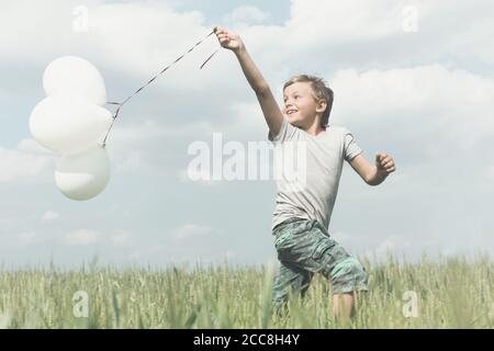 Ragazzo che si diverte con i suoi palloncini nel mezzo di natura Foto Stock