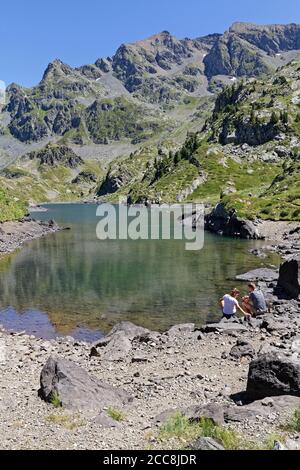 LA PRA, FRANCIA, 6 agosto 2020 : UNA giovane coppia di escursionisti riposano per un po' sul litorale di un bellissimo lago di montagna. Foto Stock