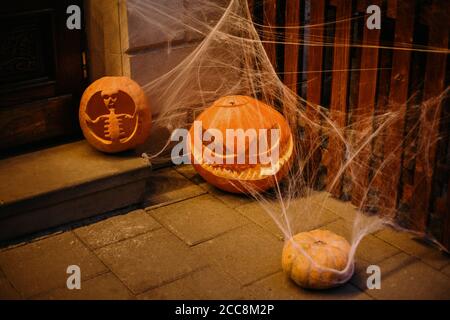 Arredamento Halloween Street. Zucche intagliate con volti spaventosi e ciottoli al buio. Decorazione moderna e festosa della via europea della città. Felice Halloween Foto Stock